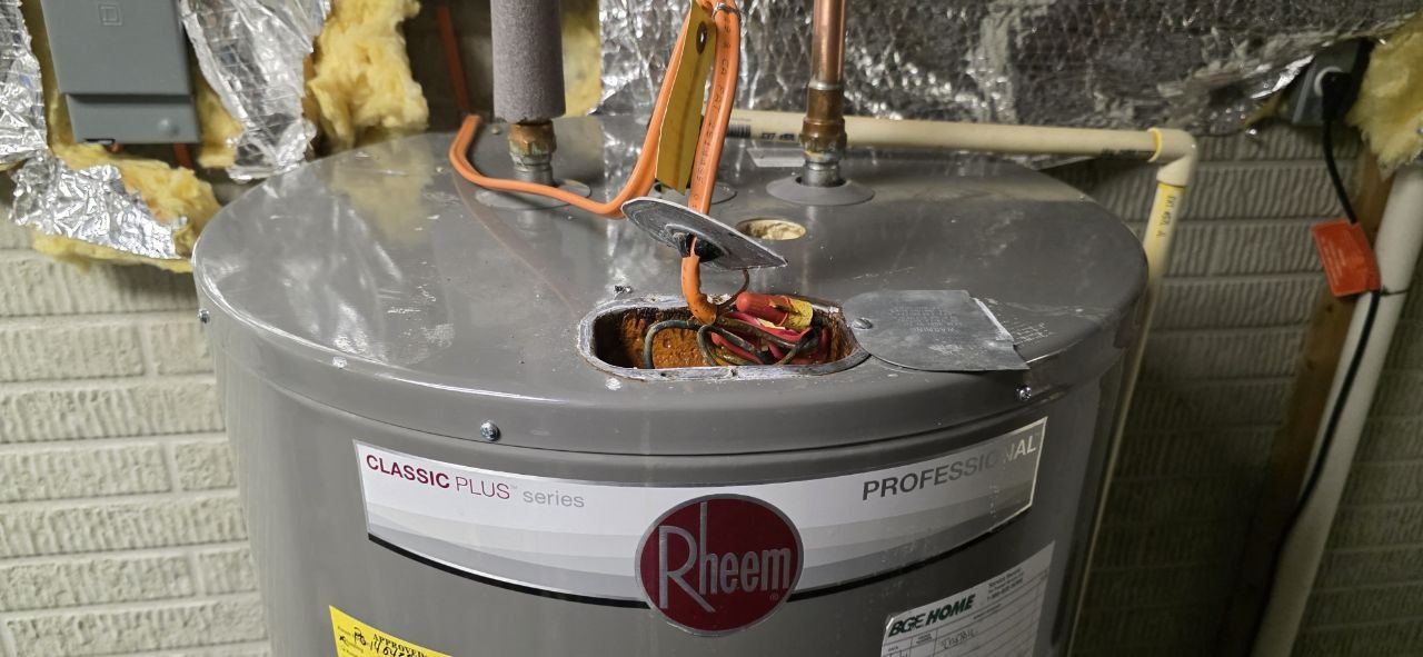 Water heater leaking near electrical components with orange corrosion deposits